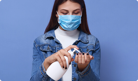 Masked woman using hand sanitizer