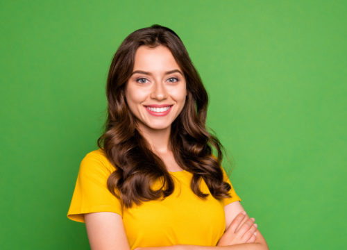 Smiling woman in a yellow shirt against a green background