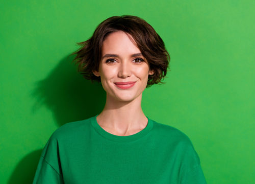 Smiling brunette woman against a green background