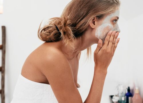 Photo of a woman applying skincare product to her face in the bathroom